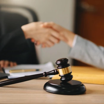a gavel on a table with a person shaking hands