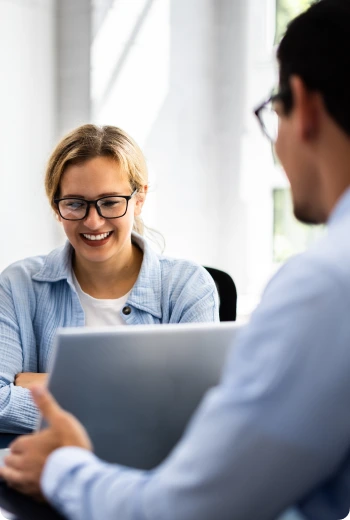 a woman smiling while holding a laptop