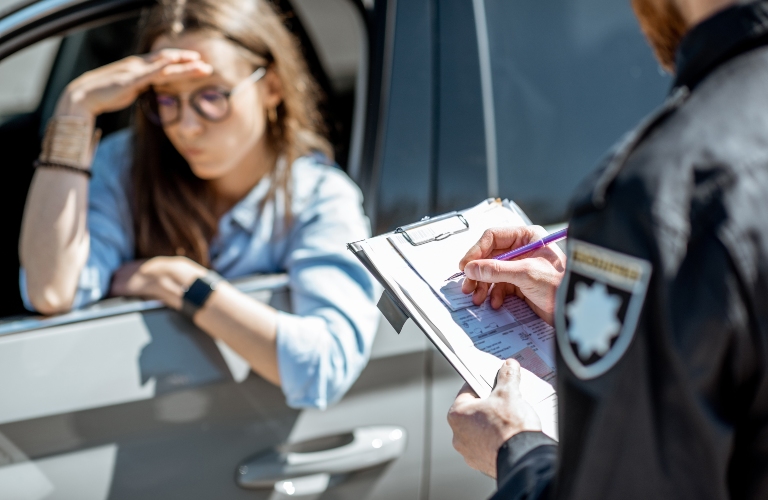 Policeman issuing a fine for violating the traffic rules to a young woman driver