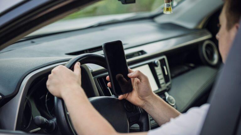 driver guy distracted by his phone while in front of the steering wheel