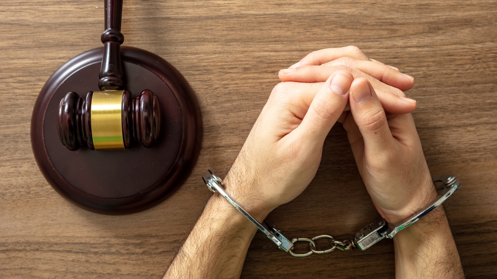 Handcuff locked and judge gavel on a wooden table