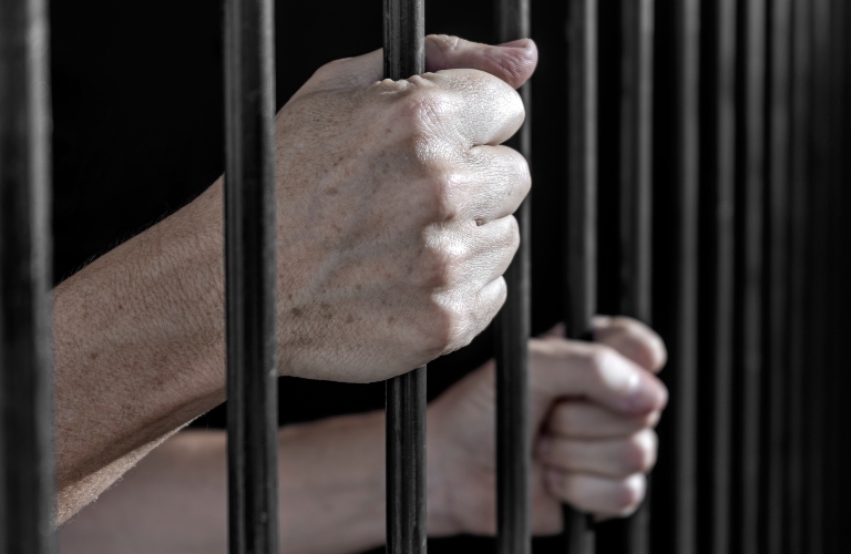 Prisoner's hands gripping the bars of a cell