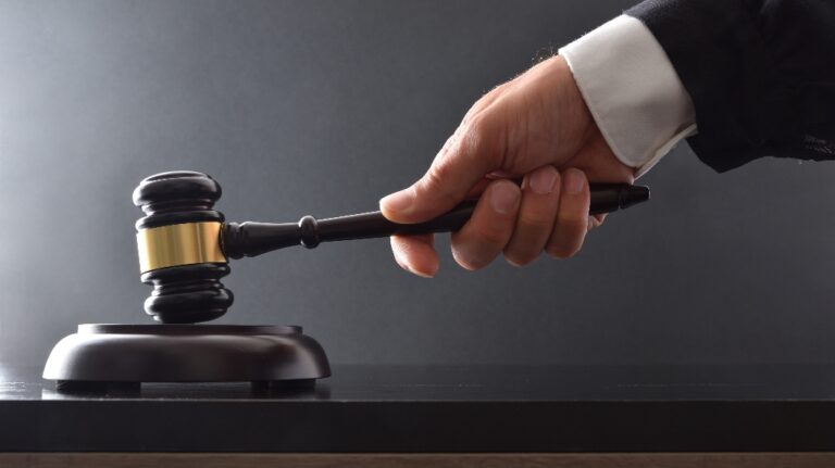 Hand striking on wooden base with judge's gavel on black table