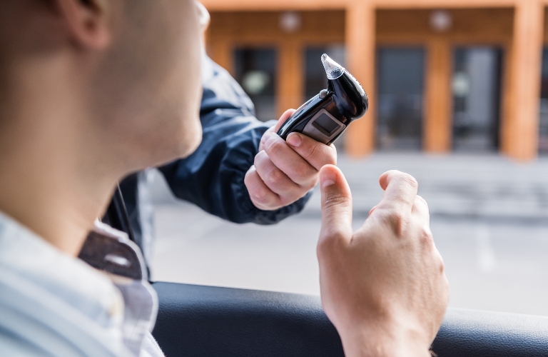 policeman giving breathalyzer to driver in car