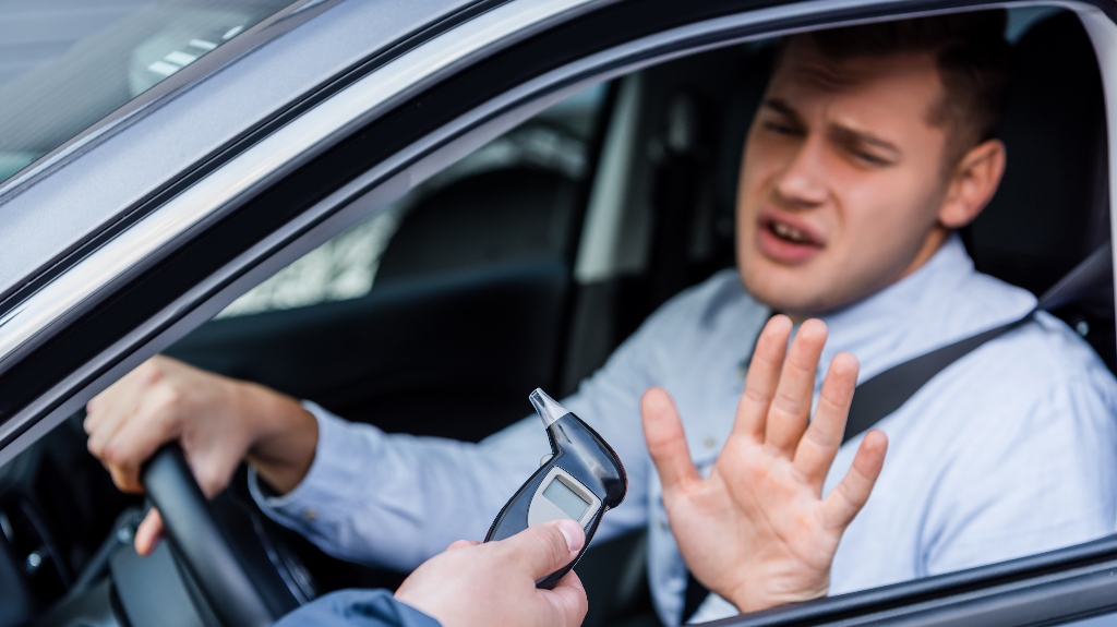 policeman giving breathalyzer to the driver