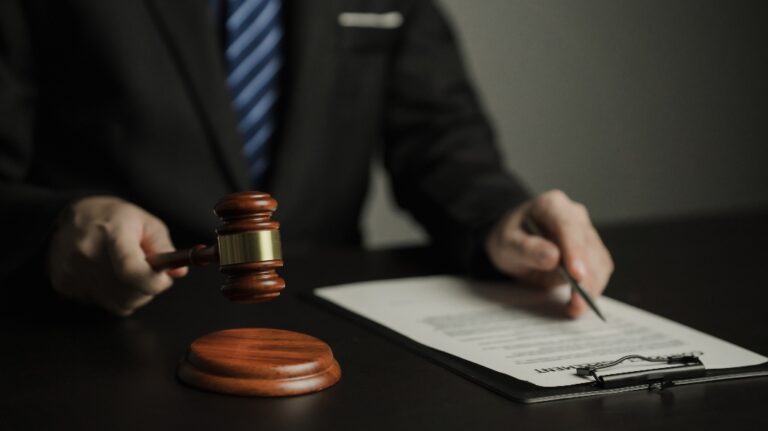man holds a judge's gavel and looks through documents