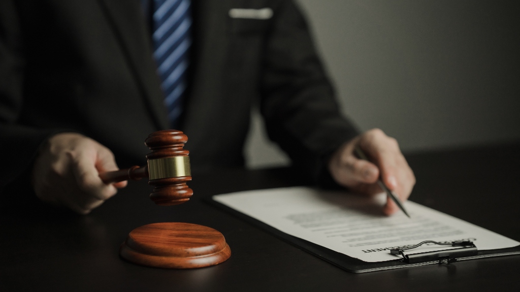 man holds a judge's gavel and looks through documents