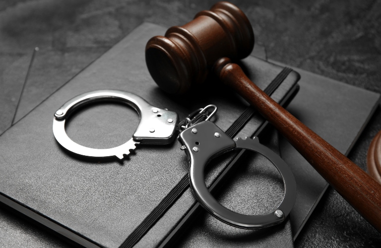 Handcuffs with judge's gavel and notebooks